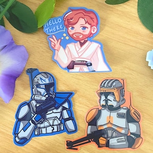 May include: A collection of colorful stickers featuring characters from a science fiction franchise. One sticker depicts a character with a speech bubble that says "Hello There". Other stickers show soldiers in armor, holding weapons.