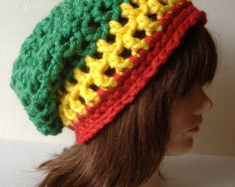 May include: Green, yellow, and red crocheted beanie hat. The hat is worn on a mannequin with brown hair.
