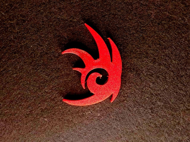 May include: A red 3D printed logo of a stylized hedgehog with a swirl in the center. The logo is on a dark brown background.