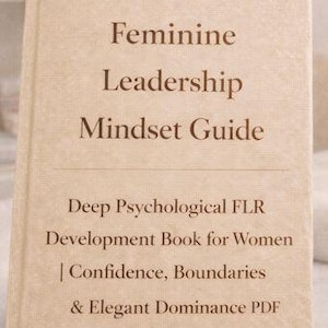 Könnte beinhalten: Ein beiges Buch mit dem Titel "Feminine Leadership Mindset Guide" mit Text über psychologische Entwicklung, Selbstvertrauen und Grenzen. Das Buch liegt auf einer weißen Oberfläche mit Nagelpflege-Werkzeugen und einer UV-Lampe im Hintergrund.