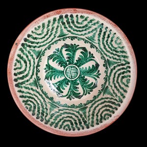 Può includere: Una ciotola rotonda in ceramica con interno color crema e bordo rosso-marrone. La ciotola è decorata con motivi floreali e a spirale verdi. Il disegno centrale è un fiore verde.