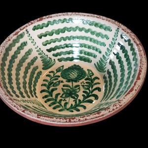 Puede incluir: Cuenco de cerámica pintado a mano con interior crema y diseño floral verde. El cuenco presenta un patrón ondulado verde en los lados y un borde marrón rojizo. El interior del cuenco tiene un diseño floral verde.