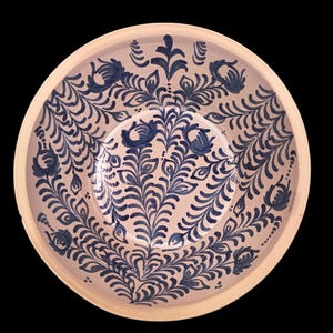 Könnte beinhalten: Eine runde, beige Keramikschale mit blauem Blumenmuster. Das Design zeigt stilisierte Blumen und Blätter, die symmetrisch angeordnet sind. Der Rand ist hellbeige. Der Durchmesser der Schale beträgt ca. 25 cm.