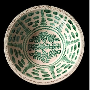 Könnte beinhalten: Eine runde, cremefarbene Keramikschale mit handbemaltem grünem Design. Das Innere der Schale zeigt ein zentrales Blumenmotiv und eine Reihe grüner Pinselstriche und Muster um den Rand. Der Rand hat einen strukturierten, braunen Rand.