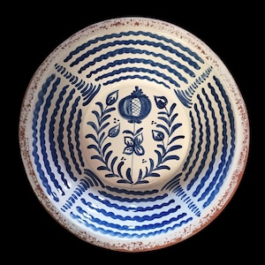 Könnte beinhalten: Eine runde, handbemalte Keramikservierschale mit weißem Innenraum und blau-weißem Streifenmuster. Die Mitte zeigt ein blaues Blumendesign. Der Rand hat einen rustikalen, rotbraunen Rand.