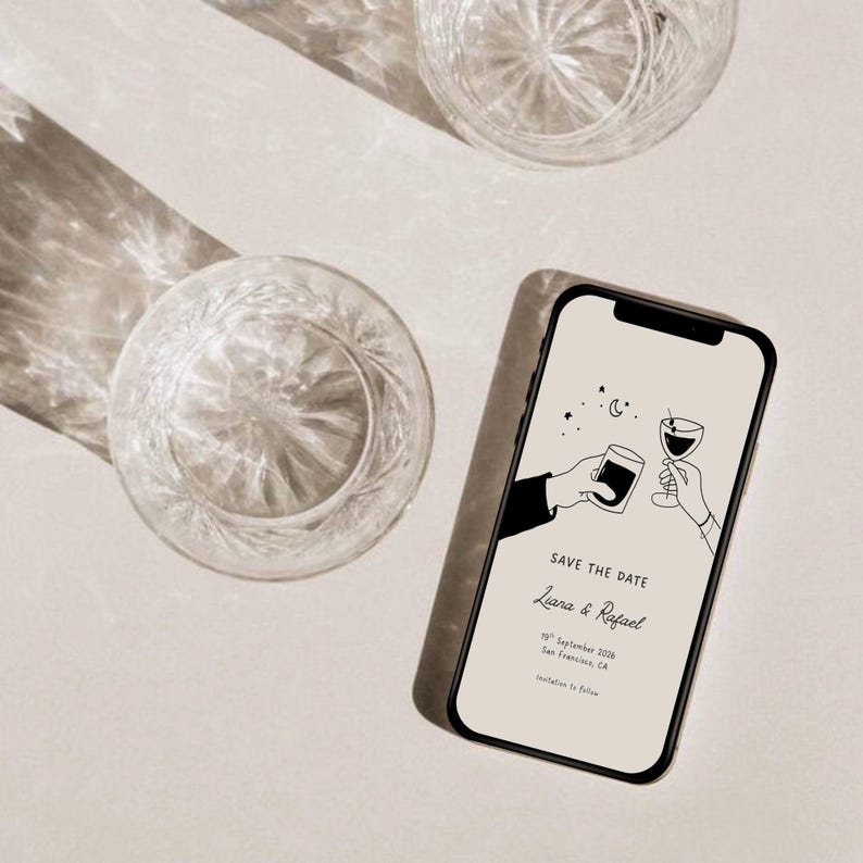 K&ouml;nnte beinhalten: Ein Smartphone zeigt eine Hochzeitseinladung mit dem Text &bdquo;Save the Date&ldquo; und den Namen &bdquo;Liana & Rafael&ldquo;. Zwei Kristallgl&auml;ser sind sichtbar, zusammen mit einem Schatten. Die Einladung zeigt eine Strichzeichnung von zwei H&auml;nden, die ansto&szlig;en.