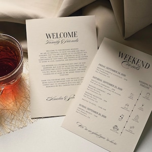 May include: Two cream-colored wedding weekend event cards with black text. One card reads "WELCOME Family Friends" and the other lists the weekend's events. A glass of tea sits in the corner.
