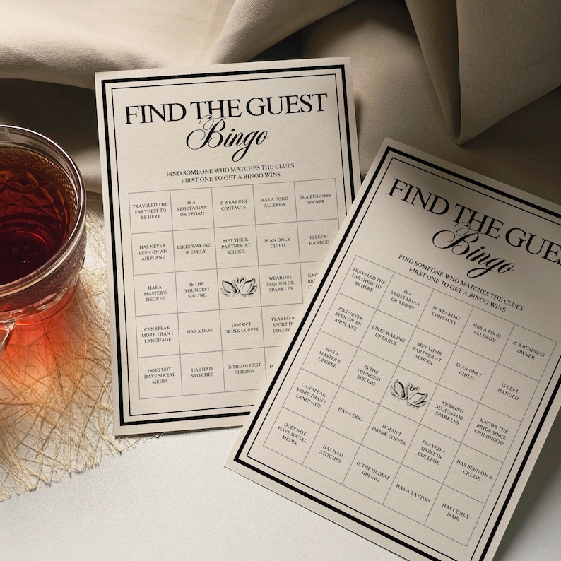 Peut inclure: Deux cartes de "Find the Guest Bingo" avec du texte noir sur fond cr&egrave;me. Les cartes ont une bordure noire et sont con&ccedil;ues pour un jeu de soci&eacute;t&eacute;. Un verre de th&eacute; est visible dans le coin.