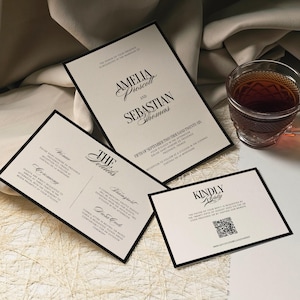 May include: Elegant wedding invitation suite with black borders and cream-colored paper. The main invitation features the names Amelia Prescott and Sebastian Thomas. Additional cards detail ceremony and reception information.