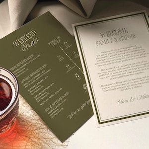 May include: Two rectangular wedding stationery cards. One olive green card lists weekend events for September 24-26, 2026, with a timeline. The second cream-colored card features a welcome message to family and friends, signed by Clara and Matthew.