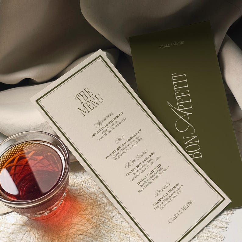 May include: A restaurant menu with a cream-colored background and a dark green menu. The menu lists appetizers, soup, main course, and desserts. A glass of red liquid sits in the lower left corner. The words "Bon Appetit" are on the green menu.