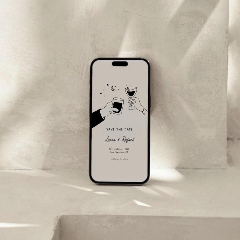 K&ouml;nnte beinhalten: Ein Smartphone zeigt eine minimalistische Hochzeitseinladung. Das Design zeigt zwei H&auml;nde, die mit einem Glas und einer Tasse ansto&szlig;en, mit Sternen und einem Mond. Der Text lautet "Save the Date" und die Namen "Liana & Rafael".