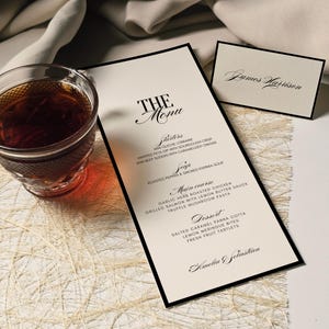 Może przedstawiać: Formalne menu z czarną obwódką, z tytułem "THE Menu" w eleganckim skrypcie. Menu zawiera przystawki, zupę, danie główne i opcje deserów. Obecna jest również mała karta z nazwiskiem "James Harrison", a także szklanka herbaty.