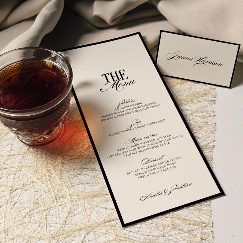 K&ouml;nnte beinhalten: Eine formelle Speisekarte mit schwarzem Rand, mit dem Titel "THE Menu" in eleganter Schrift. Die Speisekarte listet Vorspeisen, Suppe, Hauptgericht und Dessert-Optionen auf. Eine kleine Karte mit dem Namen "James Harrison" ist ebenfalls vorhanden, zusammen mit einem Glas Tee.
