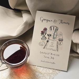 Puede incluir: Tarjeta de invitación de boda crema con los nombres "Georgina & Thomas". Ilustración acuarela de una mesa con flores, vino y texto "Save the Date". La fecha es sábado 22 de marzo de 2026, Toscana, Italia.