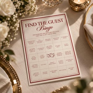 May include: A rectangular Find the Guest Bingo game card printed on white paper with dark red borders and text. The grid contains twenty-five squares with various clues, including a central illustration of two swans forming a heart shape.