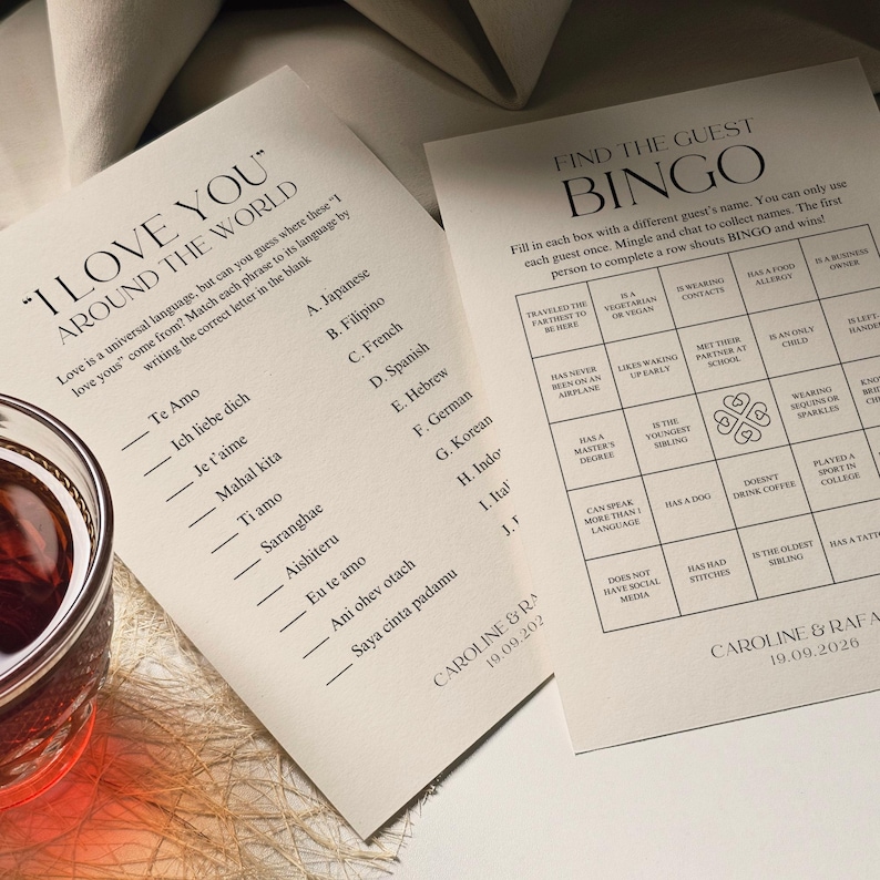 Pu&ograve; includere: Due biglietti stampati con suggerimenti per giochi di matrimonio. Un biglietto chiede di abbinare le frasi "Ti amo" alle lingue. L'altro &egrave; una scheda bingo per trovare gli ospiti con tratti specifici. Un bicchiere di liquido rosso &egrave; vicino.