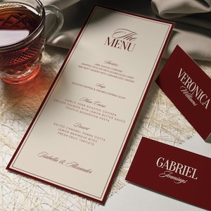 May include: A formal menu card with a claret border and text, listing dishes. The menu is titled "The Menu" in elegant script. Two matching name cards are also visible.