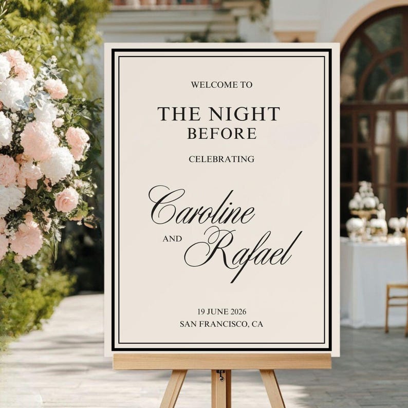 May include: A cream-colored wedding welcome sign on a wooden easel. The sign has a black border and text that reads "WELCOME TO THE NIGHT BEFORE CELEBRATING Caroline AND Rafael 19 JUNE 2026 SAN FRANCISCO, CA."