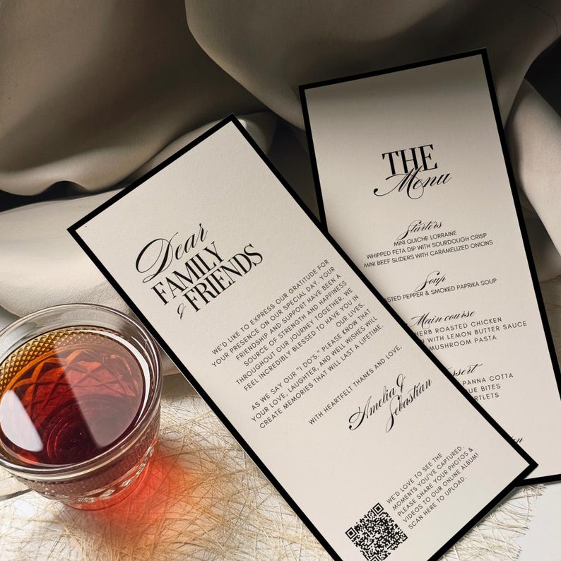 K&ouml;nnte beinhalten: Zwei elegante Hochzeitsmen&uuml;karten mit schwarzen R&auml;ndern und Kalligraphie-Text, darunter "Liebe Familie & Freunde" und "Die Speisekarte". Links steht ein Glas mit bernsteinfarbener Fl&uuml;ssigkeit. Die Men&uuml;s listen Vorspeisen, Hauptgerichte und Desserts auf.