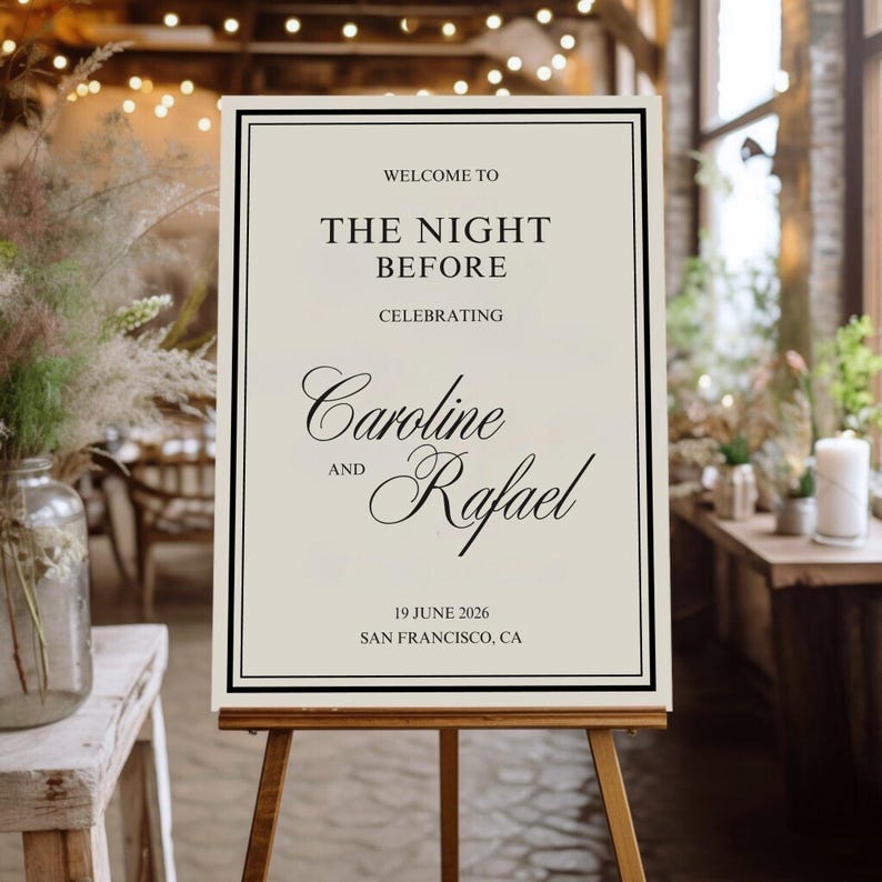 May include: A cream-colored welcome sign on a wooden easel. The sign has a black border and features elegant script that reads "Welcome to The Night Before Celebrating Caroline and Rafael 19 June 2026 San Francisco, CA."
