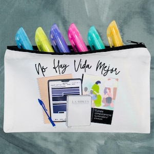 May include: White zippered pouch with the text "No Hay Vida Mejor" printed on the front. The pouch contains a variety of colorful highlighters and a drawing of a tablet, notebook, pen, and a book with the text "La Biblia" on the cover.