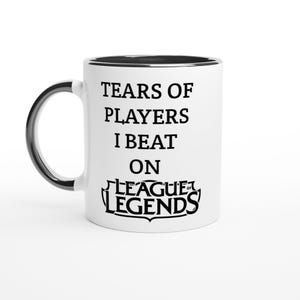 May include: White ceramic mug with a black interior and handle. The mug features the text "TEARS OF PLAYERS I BEAT ON LEAGUE OF LEGENDS" in black, a humorous statement for gamers.