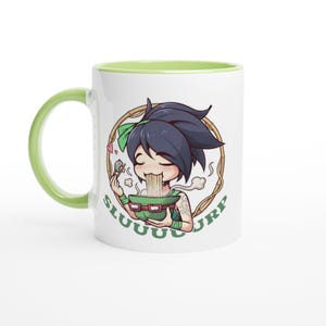 May include: White ceramic mug with a green handle and interior. The mug features a cartoon illustration of a character eating noodles from a green bowl. The word "SLUUUURP" is written around the character.