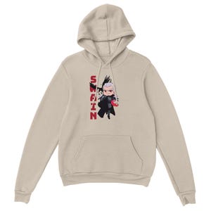 Puede incluir: Sudadera con capucha beige con una ilustración de dibujos animados de un personaje con cabello blanco y un atuendo negro. La palabra "SWAIN" está impresa verticalmente en rojo. La sudadera tiene un bolsillo de canguro y una capucha con cordón.