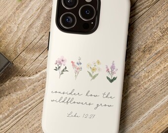 May include: A white smartphone case featuring a row of four small, delicate watercolor-style wildflowers in shades of pink, blue, yellow, and purple. Below the flowers, the text reads, "consider how the wildflowers grow" and "Luke 12:27".