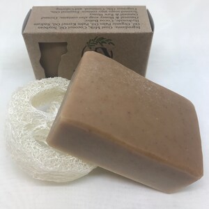 May include: A bar of brown soap with a loofah sponge. The soap is packaged in a brown box with the ingredients listed on the side. Ingredients: Goat Milk, Coconut Oil, Soybean Oil, Organic Palm Oil, Palm Kernel Oil, Sodium Hydroxide, Cocoa Butter. Oatmeal & Honey soap also contains: Ground Oatmeal & Raw Honey. Scented soaps may contain: Essential Oils, Fragrance Oils, Cornmeal, and Coloring.