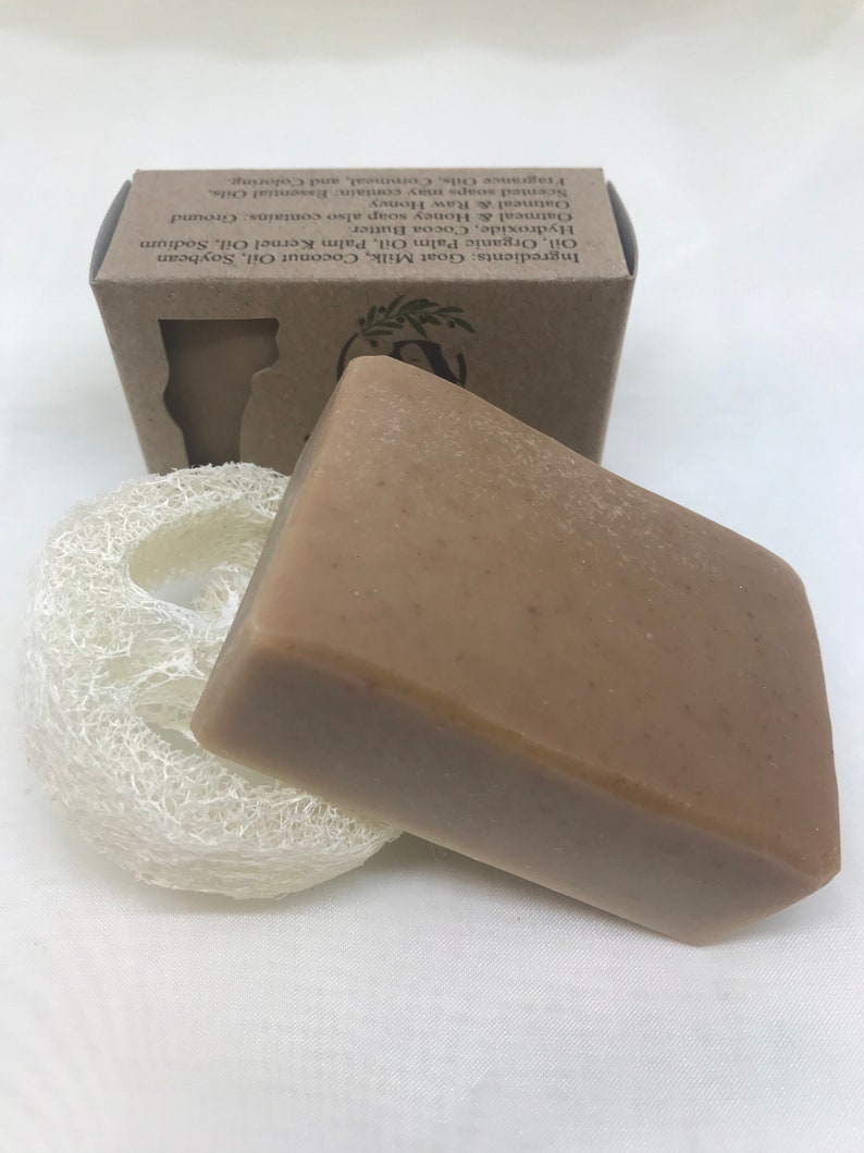 May include: A bar of brown soap with a loofah sponge. The soap is packaged in a brown box with the ingredients listed on the side. Ingredients: Goat Milk, Coconut Oil, Soybean Oil, Organic Palm Oil, Palm Kernel Oil, Sodium Hydroxide, Cocoa Butter. Oatmeal & Honey soap also contains: Ground Oatmeal & Raw Honey. Scented soaps may contain: Essential Oils, Fragrance Oils, Cornmeal, and Coloring.