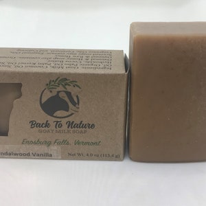 May include: A bar of brown goat milk soap with a label that reads "Back To Nature Goat Milk Soap", "Enosburg Falls, Vermont", and "Sandalwood Vanilla". The soap is packaged in a brown cardboard box with a goat logo.