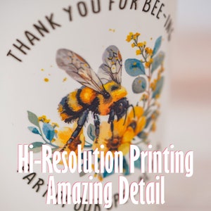 Image showcasing a personalized plastic stadium cup with a detailed bee design and the text 'Thank You for Bee-ing Here.' Highlights high-resolution printing and amazing detail, perfect for custom gifts and party favors