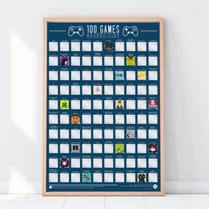 May include: A dark blue scratch-off poster titled 100 GAMES BUCKET LIST in a light wood frame. The poster features a grid of white squares, some of which are scratched off to reveal colourful game-themed illustrations and text labels for each game.