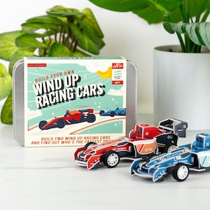 May include: A DIY STEM kit with a tin case that reads "Build Your Own Wind Up Racing Cars." The kit includes two wind-up race cars, one red and one blue, with the number 25 on them. The kit is for ages 8+.