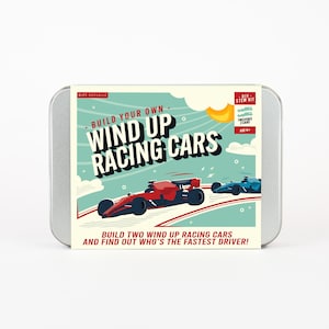 May include: A metal tin featuring a DIY STEM kit for wind-up racing cars. The box art shows two race cars, one red and one blue, racing on a track. Text on the box reads "Build Your Own Wind Up Racing Cars" and "Build two wind up racing cars and find out who's the fastest driver!"