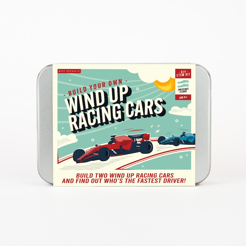 May include: A metal tin featuring a DIY STEM kit for wind-up racing cars. The box art shows two race cars, one red and one blue, racing on a track. Text on the box reads "Build Your Own Wind Up Racing Cars" and "Build two wind up racing cars and find out who's the fastest driver!"