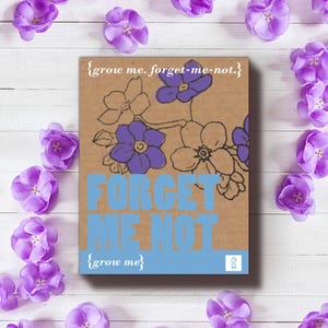 May include: A brown paper card with a blue border and the text "{grow me. forget-me-not.}" and "{grow me}". The card features a drawing of forget-me-not flowers in purple and black.