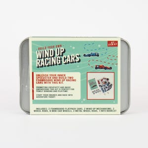 May include: A DIY STEM kit in a silver tin. The kit includes two foamboard flatpack cars, wind-up mechanisms, wheels, and a booklet. The box features the text "Build Your Own Wind Up Racing Cars" with illustrations of race cars.