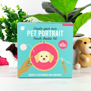 May include: A blue and white box with the text "Create your own PET PORTRAIT Punch Needle Kit" and a picture of a dog's head on a pink background. The box includes all materials needed to create a custom pet portrait.