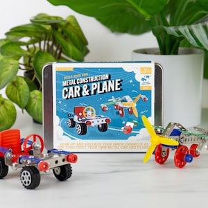 May include: A metal construction kit for building a car and plane. The kit includes a tin with the words "Build Your Own Metal Construction Car & Plane". A red and blue car and a plane with a yellow propeller are assembled.