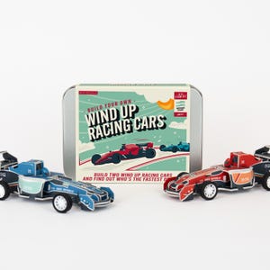 May include: A DIY STEM kit for building wind-up racing cars. The kit includes a metal tin with the text "Build Your Own Wind Up Racing Cars" and two assembled race cars in red and blue. The cars have the number 25 on them.