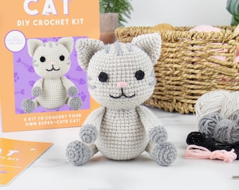 May include: A DIY crochet kit to make a gray and white cat. The kit includes yarn, needles, and instructions. The finished cat is sitting on a white surface.