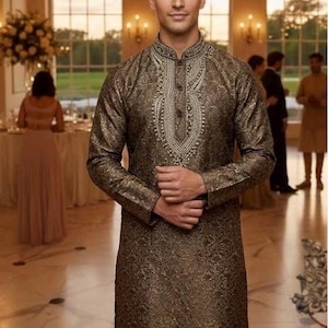 May include: A long-sleeved, knee-length bronze-colored kurta featuring an intricate tonal paisley pattern throughout the fabric. The garment includes a high mandarin collar and a central placket adorned with detailed silver-toned embroidery.
