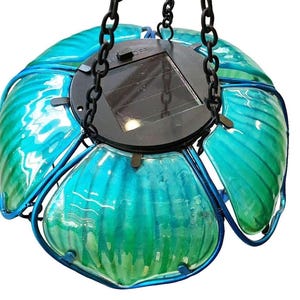 A hanging glass pendant light with a floral design, featuring multiple green glass petals and a black base.