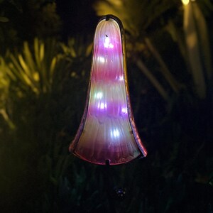A glowing, illuminated object resembling a flower or plant stands out against the dark background.
