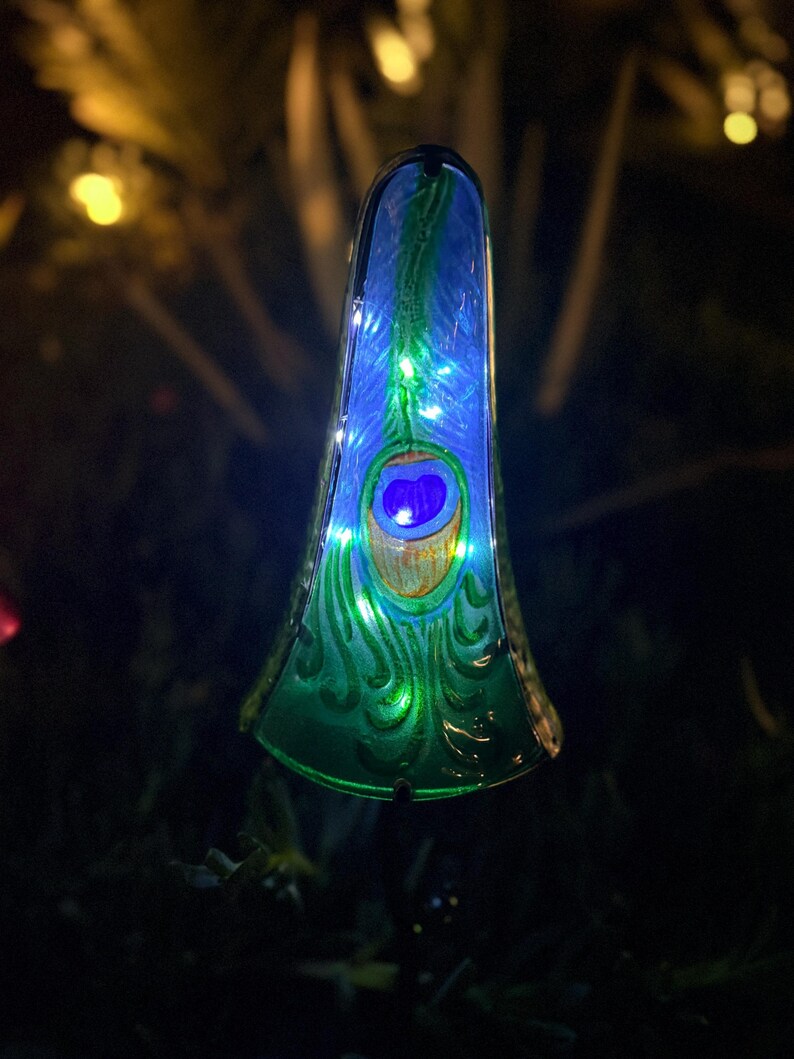 A colorful, illuminated glass ornament resembling a peacock feather is displayed in the image.