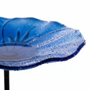 A close-up view of a blue glass plate with water droplets on its surface, creating a shiny, reflective effect.