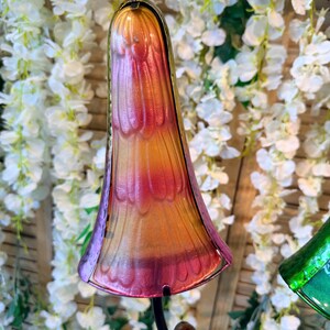 a colorful glass sculpture with a vibrant, multi-colored design, set against a backdrop of white flowers.